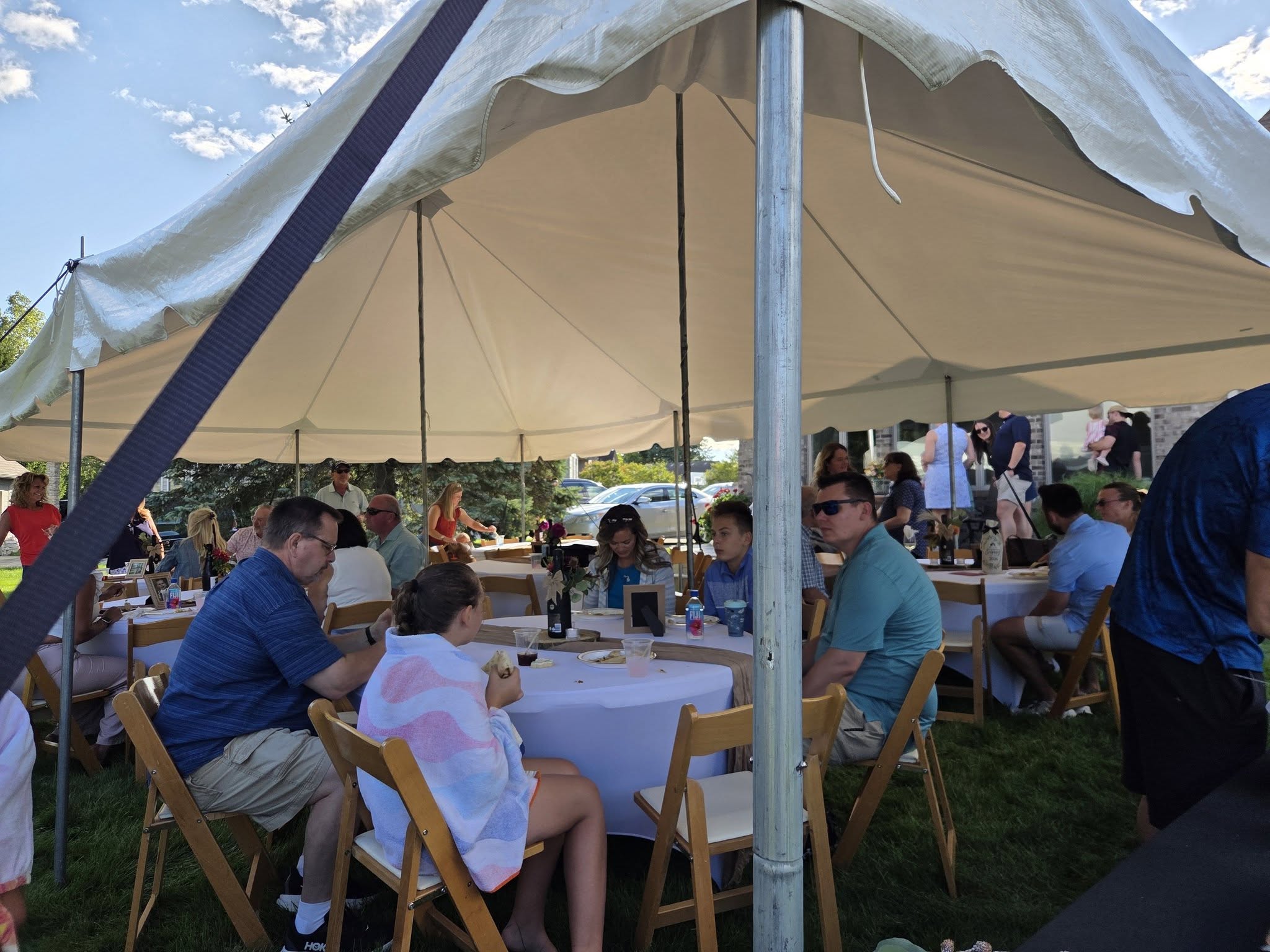 Guests seated at tables under a white event tent
